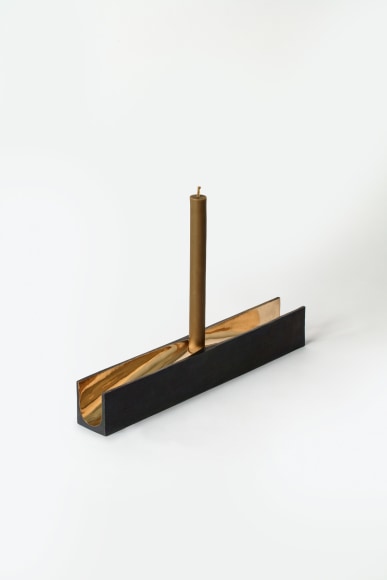 bronze with beeswax candle holder photographed on a grey background.
