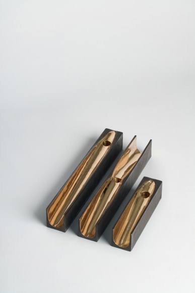 bronze with beeswax candle holder photographed on a grey background.