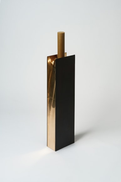 bronze with beeswax candle holder photographed on a grey background.