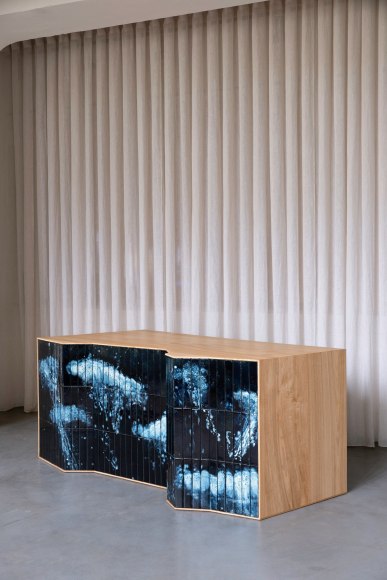 Desk made of oak and tiles by made in situ . Blue and brown sitting in a grey room.