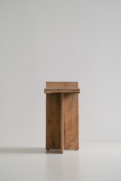Side table made of oak and cork with a slant and photographed on grey background.