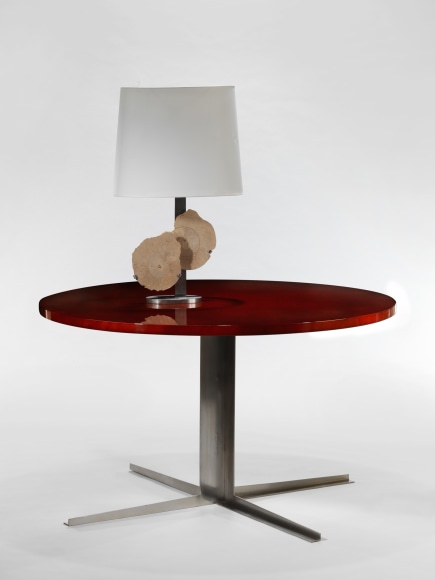 photo of a red dining table in a white room with a lamp on top