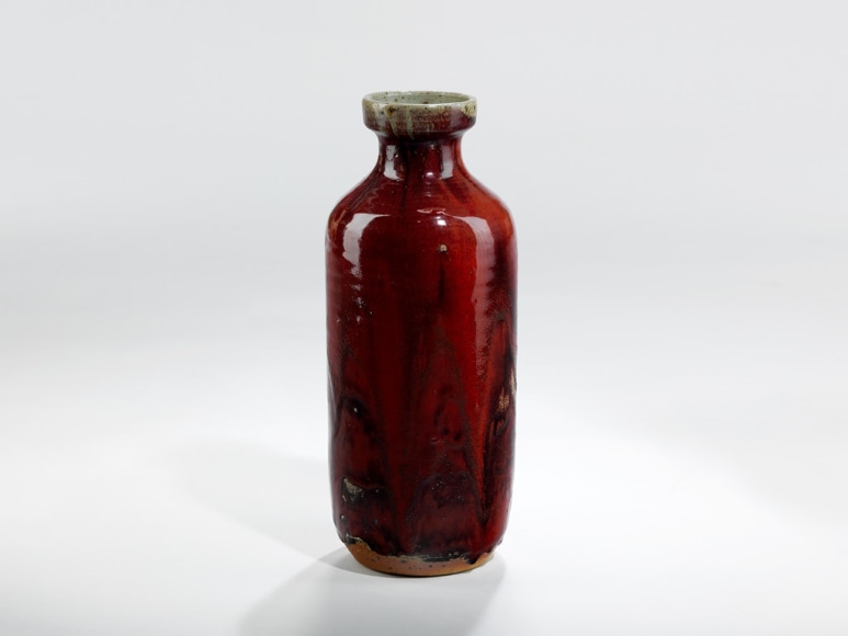 picture of a red vase in a grey room