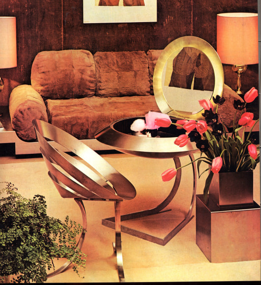 Metal cone-like chair in front of a metal vanity and upholstered day bed behind