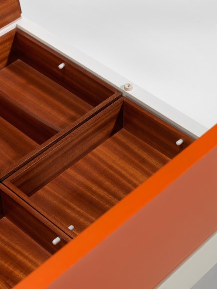 photograph of low table by Motte in a blank room, top of table is half orange and half white