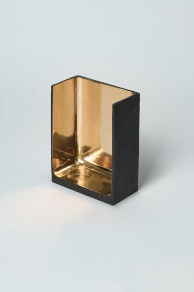 Bronze candlestick with gold detailing and black exterior.