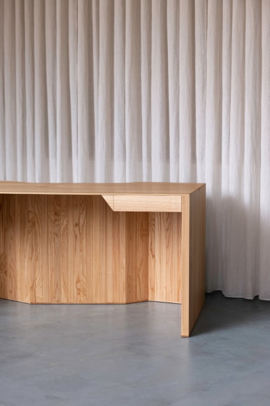 Desk made of oak and tiles by made in situ . Blue and brown sitting in a grey room.
