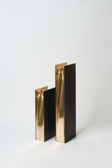 bronze with beeswax candle holder photographed on a grey background.