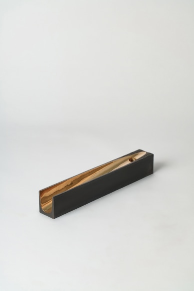 bronze with beeswax candle holder photographed on a grey background.