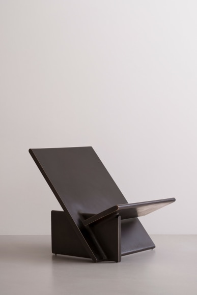 Blackened bronze lounge chair with intersecting planes