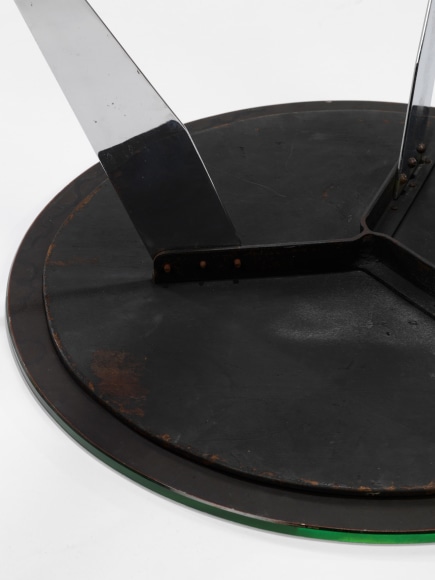 photograph of table in a blank room with metal legs and a glass top