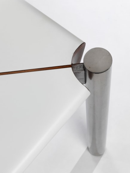 Detail view of corner where white formica table meets stainless steel legs