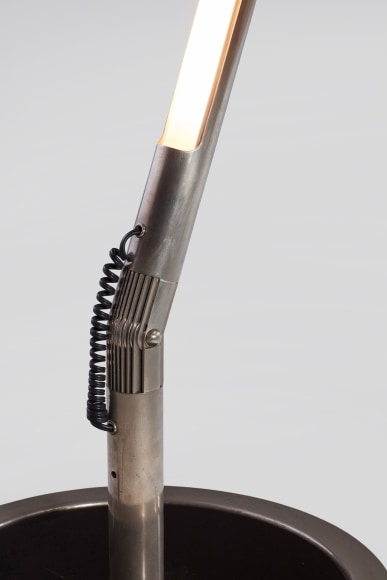 photograph of long metal floor lamp in a blank room