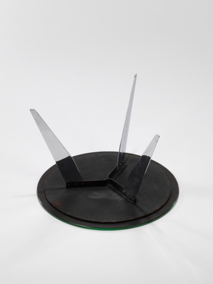 photograph of table in a blank room with metal legs and a glass top