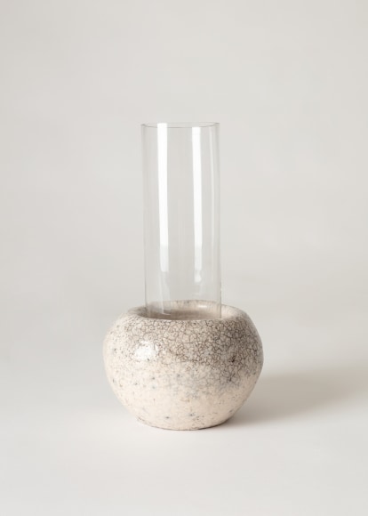 Clear glass tubular vase sitting inside raku ceramic holder.