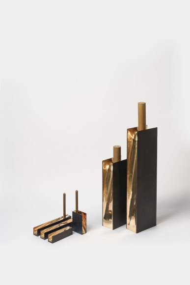 bronze with beeswax candle holder photographed on a grey background.