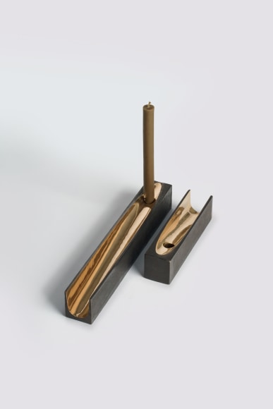 bronze with beeswax candle holder photographed on a grey background.