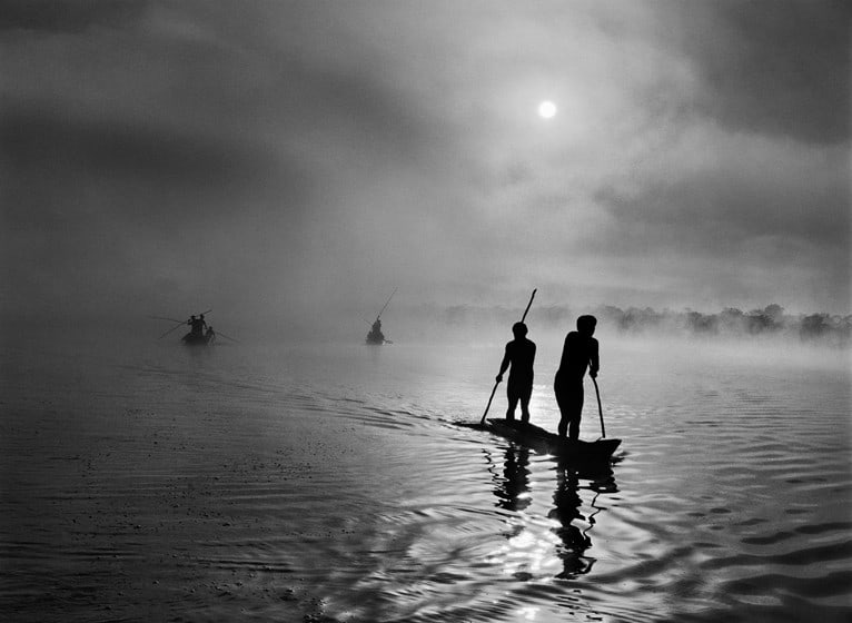 Sebastião Salgado, At daybreak, Waurá Indians travel by canoe to collect the “waiting net,” Xingu Indigenous Territory, state of Mato Grosso, Brazil, 2005, gelatin silver print, 91.4 x 127 cm (36 x 50 inches) © Sebastião Salgado