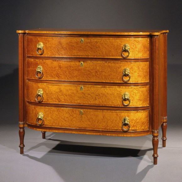 Bowfront Chest of Drawers in the Sheraton Taste, about 1815 Eastern Massachusetts, probably Boston, possibly Thomas Seymour. Cherry, mahogany, bird&rsquo;s eye maple, striped maple, and ebony, with original gilt-brass lion-head pulls. 37 5/16 in. high, 43 5/8 in. wide, 23 7/16 in. deep