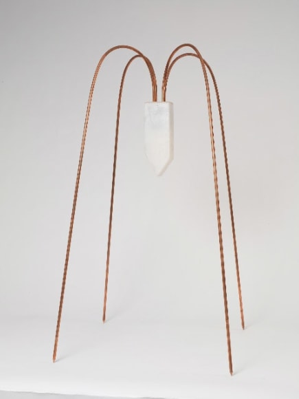 a sculpture by Maria Elena Gonzalez of a house-shape hanging upside down from four, thin copper legs