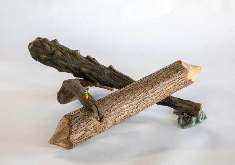 a sculpture by Lily Cox-Richard of a beaver-gnawed piece of wood, a plastic "wooden" club and a piece of driftwood in a triangular shape held together with a pencil