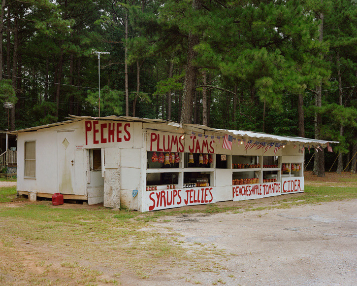 Horizontal photograph of an old white road side fruit stand