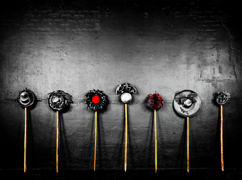 Photograph of tobacco sticks with hats propped on top in a line