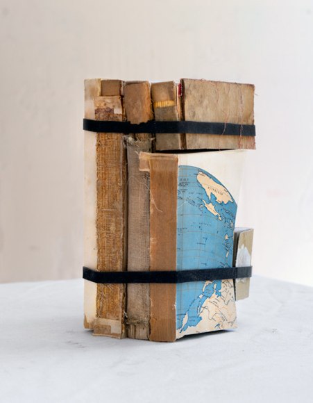 James Henkel  Map From the Series Books, 2020  30h x 24w in 76.20h x 60.96w cm  Edition 5  JHe_059 4 books strapped together; 3 undamaged and 1 that has had everything beneath the top portion cut off and placed on top of a different book that has had it's top portion cut off in what seems like the same spot