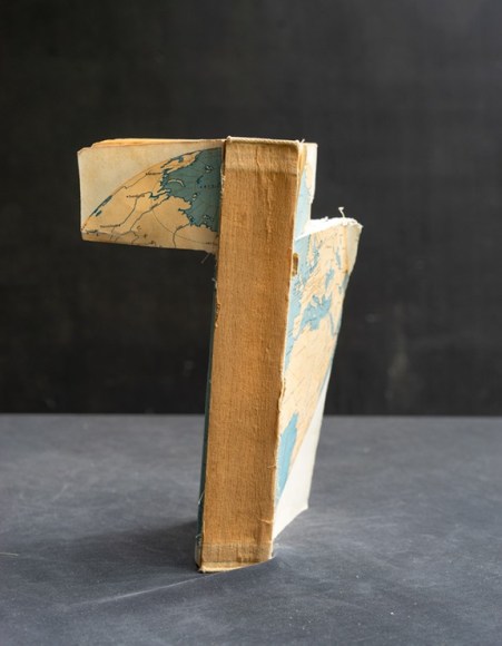 James Henkel  Divided Map From the Series Books, 2020  20h x 16w in 50.80h x 40.64w cm  Edition 5  JHe_056 a sideview of a single book with portions bended to face the viewer and features a map of earth