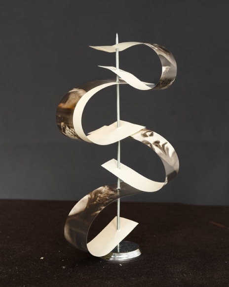 Photograph of other cut photographs pierced and bent on a spindle.