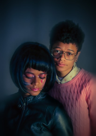 Self portrait of artist in an old school portrait session pose. Their work deals with  scrutiny, legislation, and emotional erosion that marginalized identities endure.