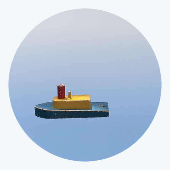 Photograph of wooden boat sculpture on circular blue background, by Workingman Collective