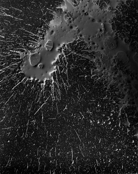 Ben Nixon  Twenty Shades of Gray, 2015  unique silver gelatin photogram  10h x 8w in   Framed: 20h x 16w in. a photogram of a large hook shaped area of silver over a black backgroud