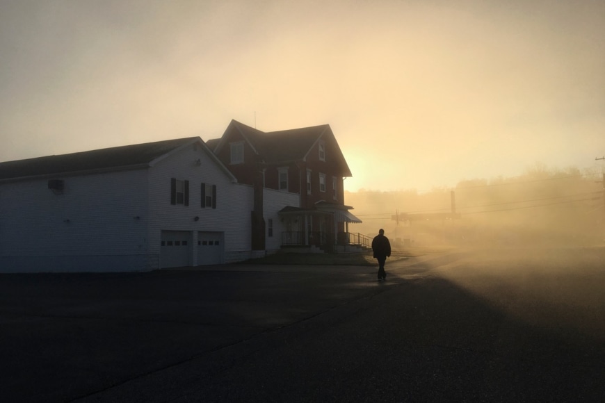 Stacy Kranitz  Mason, West Virginia, 2016  Archival Pigment Print  16 x 24 inches, Edition of 7  27 x 40 inches, Edition of 3, Shadowed man in front of a house at sunset, West Virginia