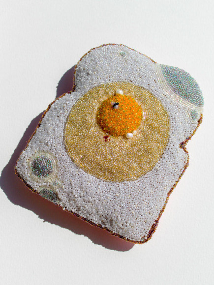 soft sculpture with hand embroidery of piece of toast with egg