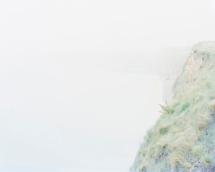 Ponte du Hoc, Artlantic Wall Fortifications (France), 2017  Archival Pigment Print  30 x 37.5 inches  Edition of 5, image of the coastline with wall fortifications and greenery in middle right side of image.