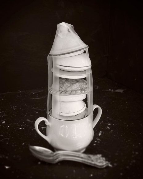 Black and white photograph of stacked and bound porcelain lids, by James Henkel
