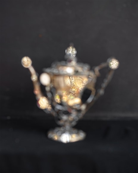 out if focus silver tea pot with small round  mirrors reflecting a landscape (in focus)