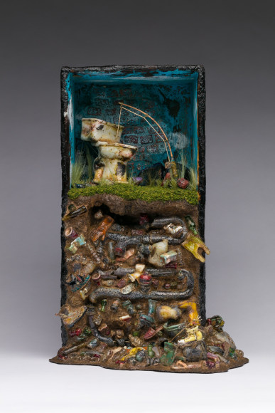 Box sculpture featuring a toilet with a fishing rod coming out of the bowl, sitting on top of a mountain of trash