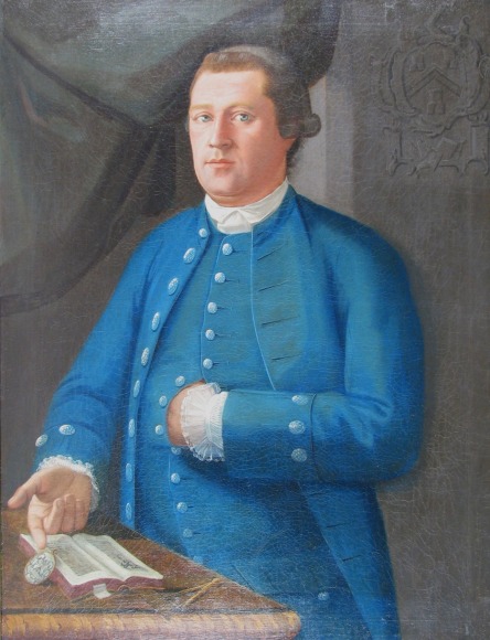 Image of oil painting by John Mare titled &quot;Man in Blue&quot; showing a man in a blue coat and vest, standing next to a table or desk with a book and locket on it.