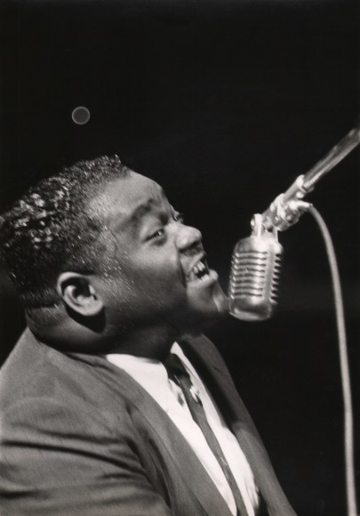 Charlotte Brooks, Fats Domino, c. 1960. Subject sings into a microphone, blurred with motion, facing right.