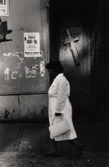 14. Beuford Smith, Sunday, Harlem Women, ​1966. A woman in white in profile as she walks towards the left of the frame.