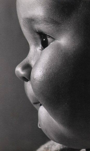 48. Peter N. Johns, Lisa, c. 1962. Close up of a drooling baby in profile, facing the left of the frame.