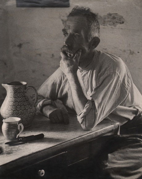 43. Felix H. Man, Unemployed, c. 1955. A man sits at a table set with a pitcher and mug, one hand to his face, gazing to the left of the frame.