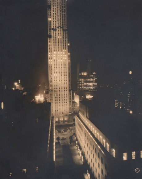 Paul J. Woolf, RCA Building from Plaza, ​c. 1935. Night time scene with tallest building alit and dividing the frame vertically.