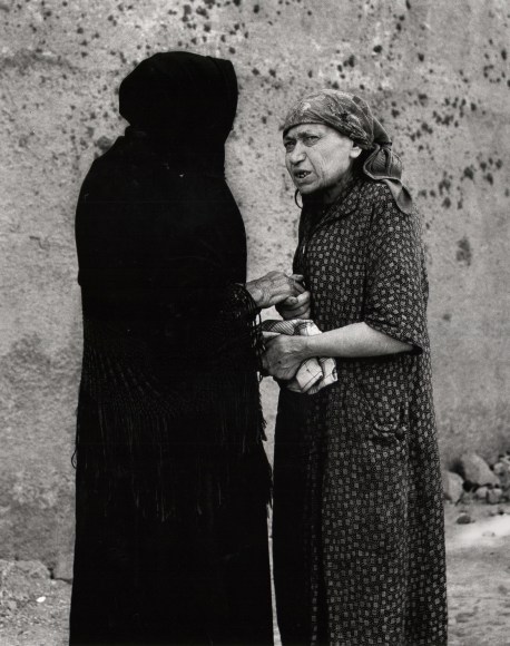 Nino Migliori, The Widow, 1956. Two woman talk on the street. One is wearing all black.