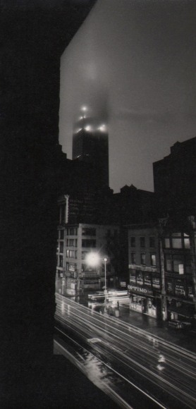 41. W. Eugene Smith, As From My Window I Sometimes Glance, ​1957&ndash;1958. Nighttime elevated view of city street. The tallest building reaches into the fog.