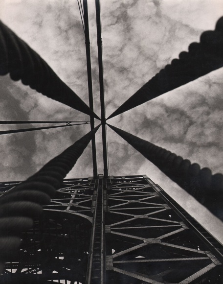 Gerard Oppenheimer, George Washington Bridge: Detail, ​c. 1955. Camera points up in the middle of four ropes extending upward towards a cloudy sky.