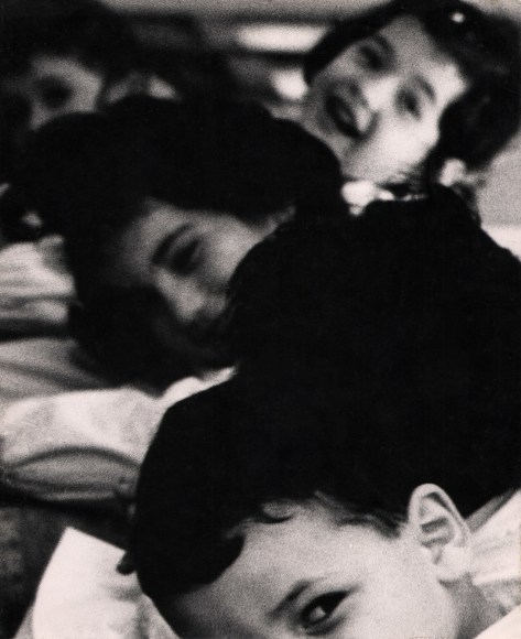 20. Renzo Tortelli, Piccolo Mondo, 1958&ndash;1959. High contrast image. A row of children extending back from the lower middle frame, faces smiling towards the camera.