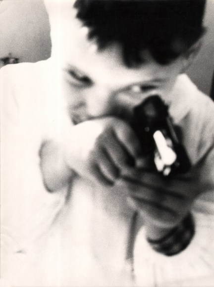 19. Renzo Tortelli, Piccolo Mondo, 1958&ndash;1959. High contrast image. Close up of a young boy holding a toy gun to his face as if to aim towards the bottom right of the frame.